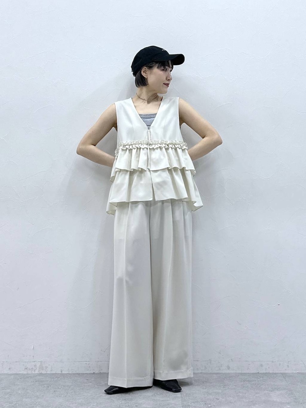 グレー系のタンクトップ、ブラック系のキャップを着用したレディースの春コーディネートの2枚目の写真