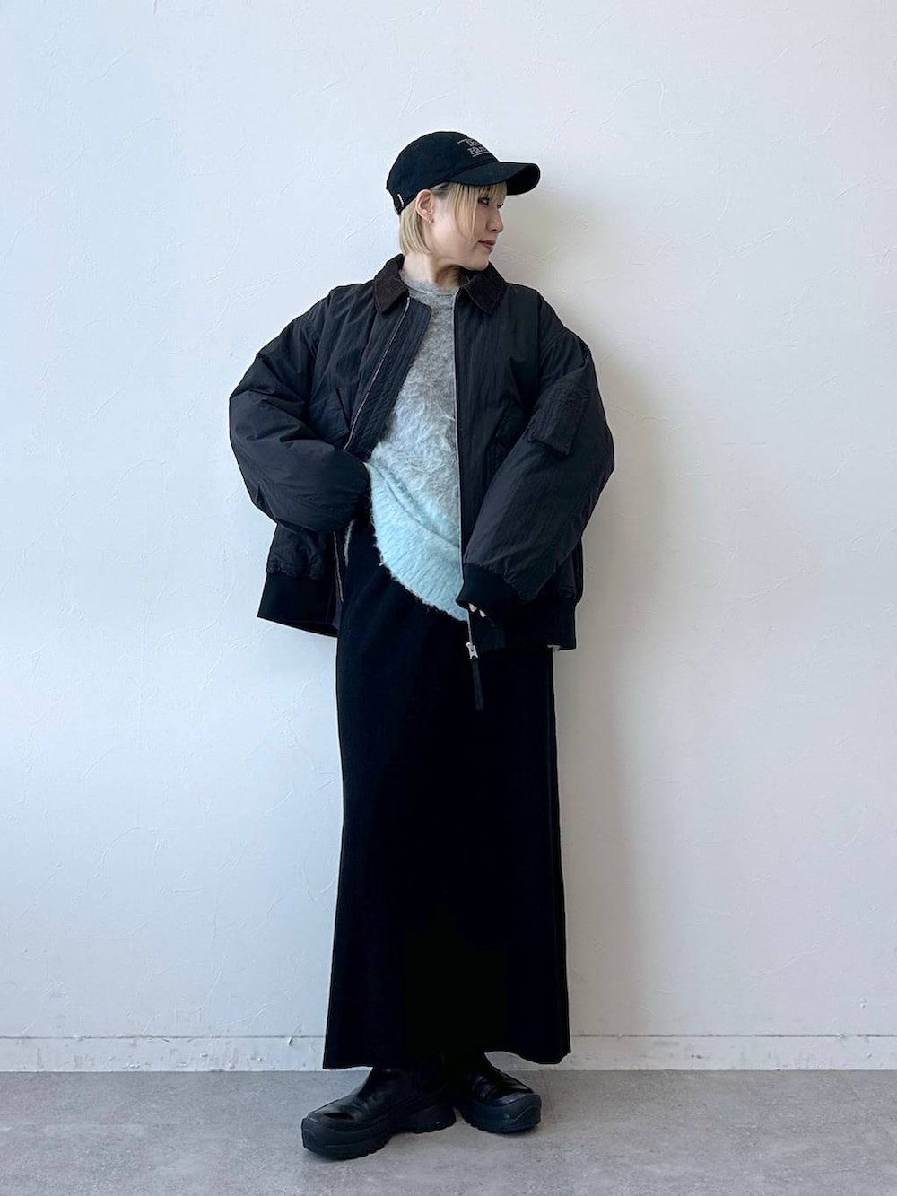 ブラック系のブルゾン、グレー系のニット/セーター、ブラック系のスカートを着用したレディースの冬コーディネートの2枚目の写真