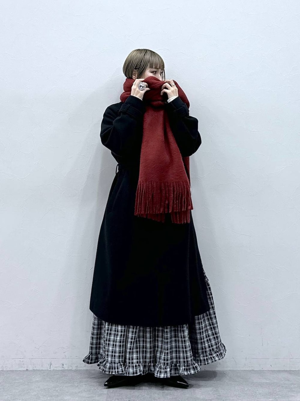 ブラック系のステンカラーコート、ブラック系のスカート、ブラック系のパンプスを着用したレディースの冬コーディネートの2枚目の写真