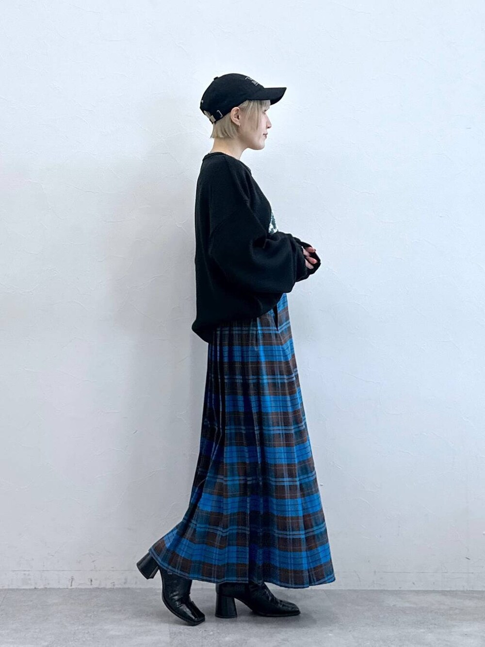 ブラック系のニット/セーター、ブルー系のスカート、ブラック系のキャップを着用したレディースの秋コーディネートの4枚目の写真