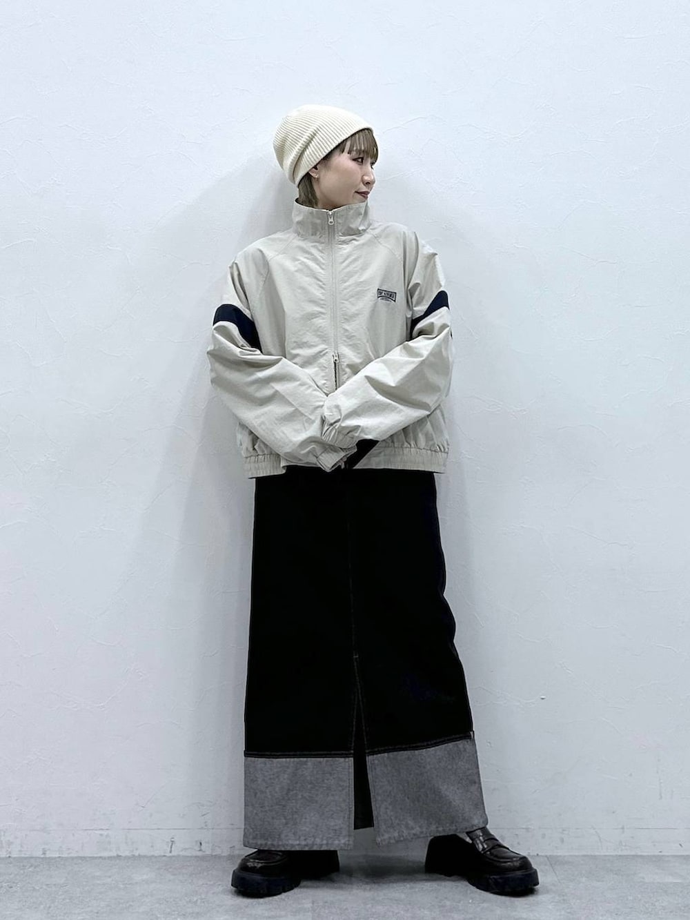 ブラック系のローファー、ホワイト系のブルゾン、ブラック系のデニムスカートを着用したレディースの冬コーディネートの4枚目の写真