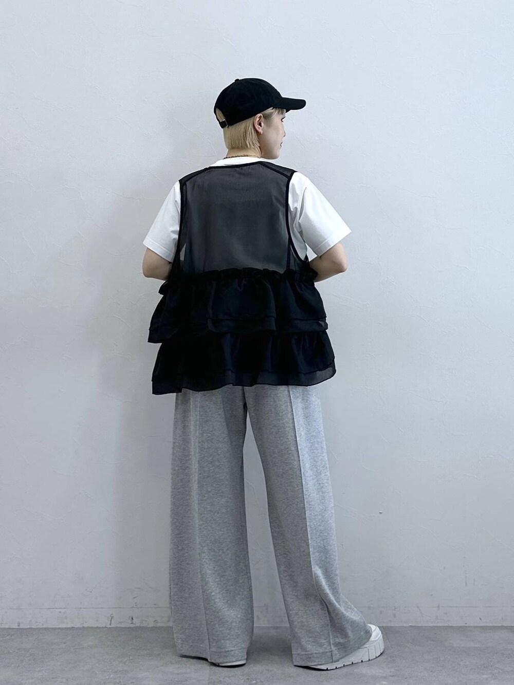 グレー系のスウェットパンツ、ホワイト系のTシャツ/カットソー、ブラック系のベストを着用したレディースの春コーディネートの6枚目の写真