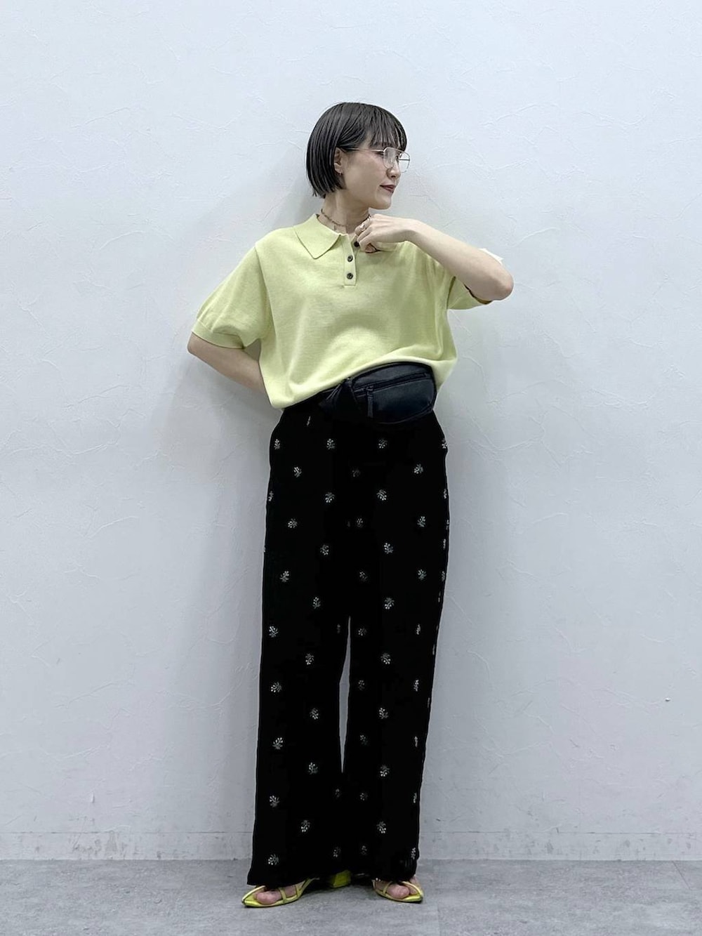 ブラック系のボディバッグ/ウエストポーチ、イエロー系のポロシャツ、ブラック系のスラックスを着用したレディースの春コーディネートの2枚目の写真