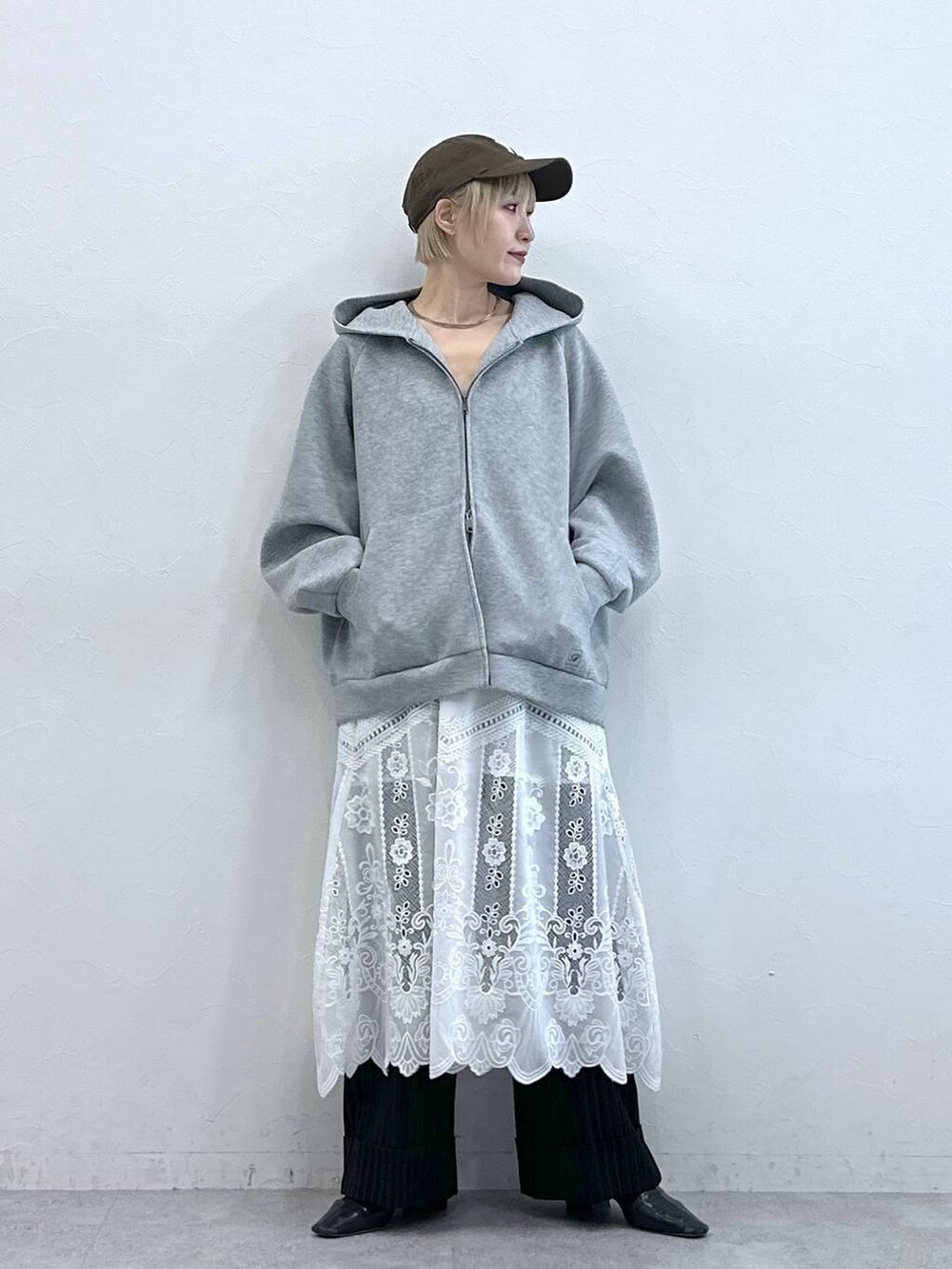 ブラウン系のスラックス、ホワイト系のスカート、グレー系のパーカーを着用したレディースの秋コーディネートの4枚目の写真