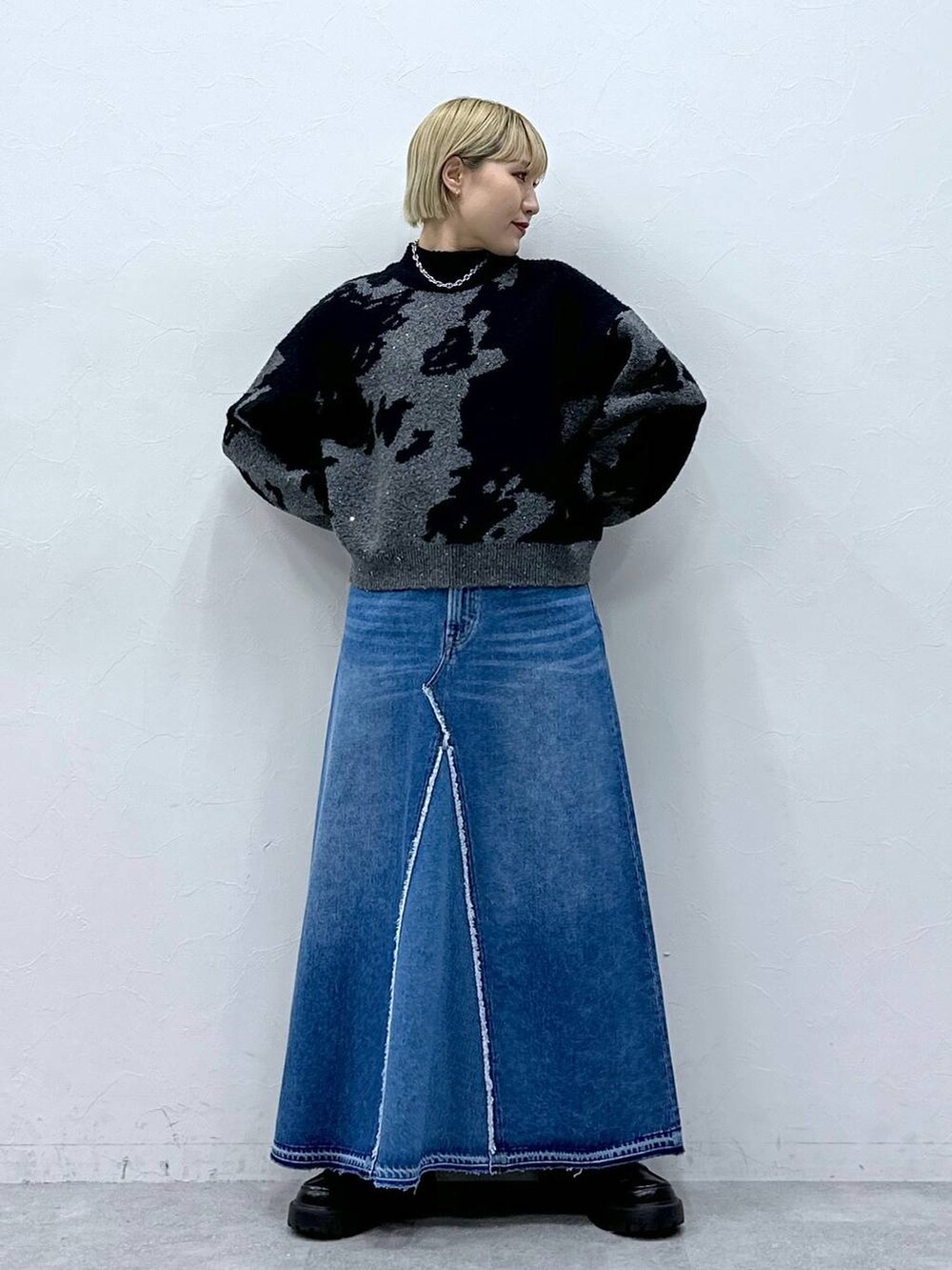 ブルー系のデニムスカート、ブラック系のニット/セーター、ブラック系のローファーを着用したレディースの冬コーディネートの2枚目の写真