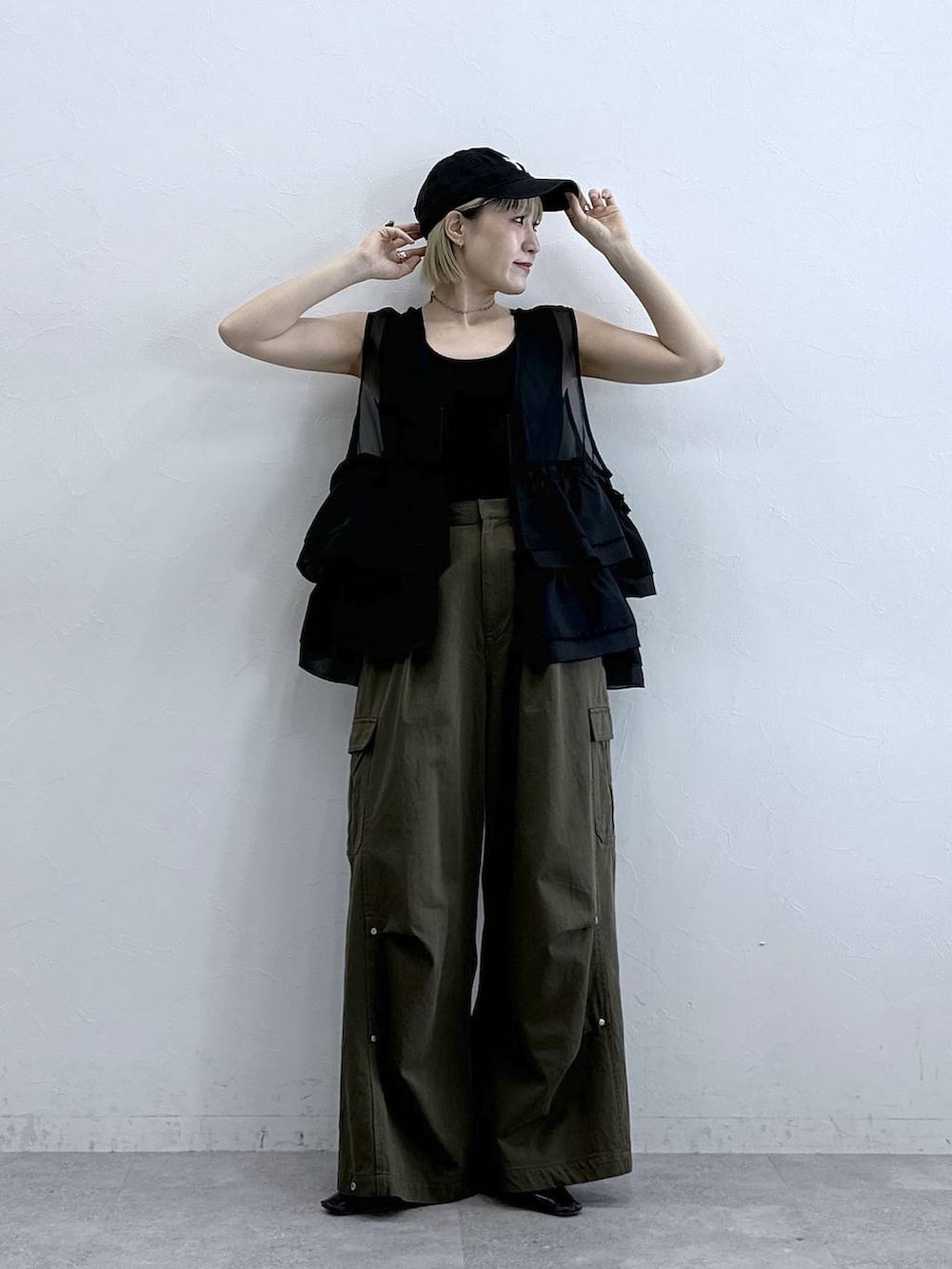 グリーン系のカーゴパンツ、ブラック系のタンクトップ、ブラック系のベストを着用したレディースの夏コーディネートの3枚目の写真