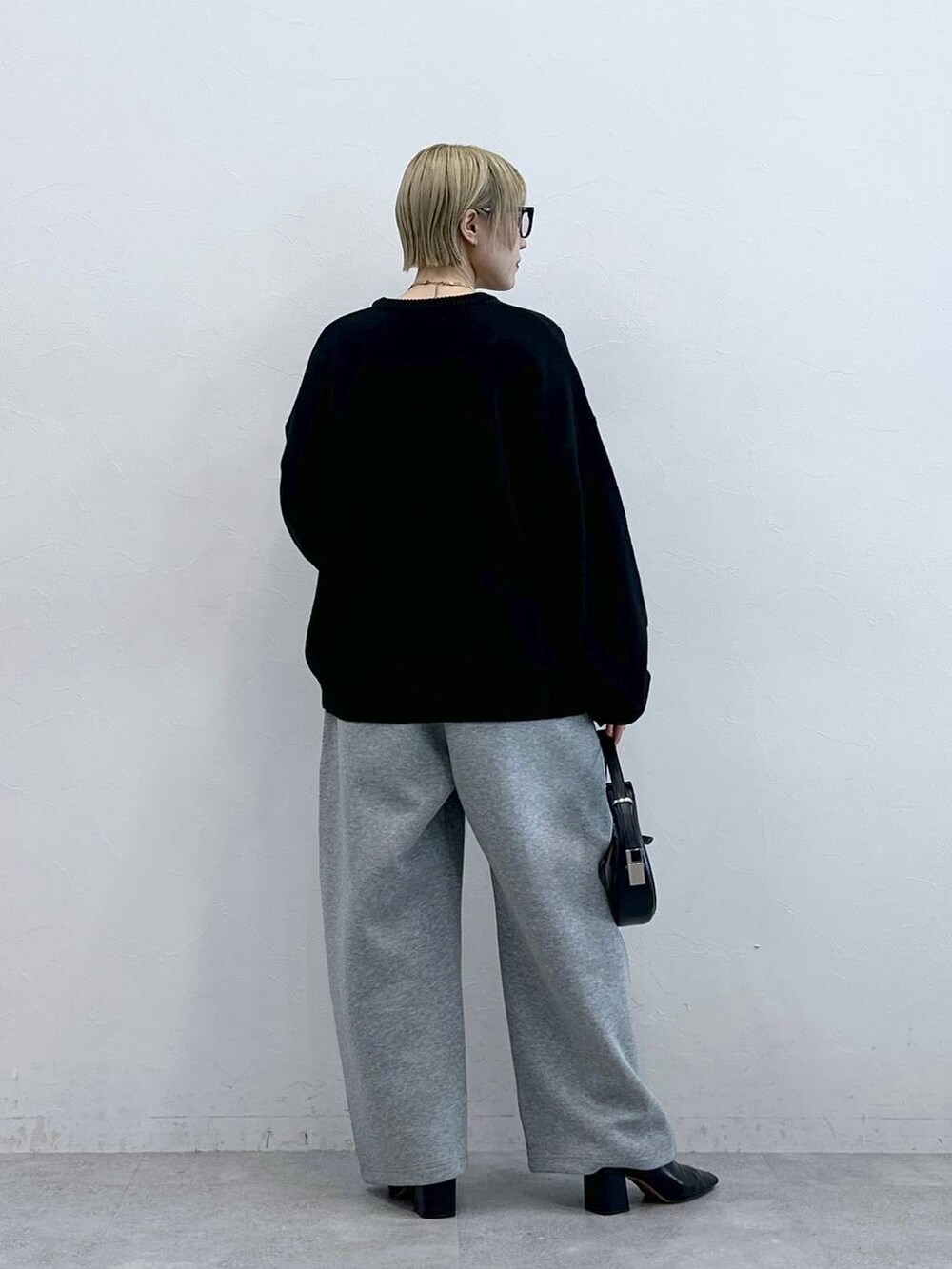 ブラック系のニット/セーター、グレー系のスウェットパンツ、グレー系のメガネを着用したレディースの秋コーディネートの5枚目の写真