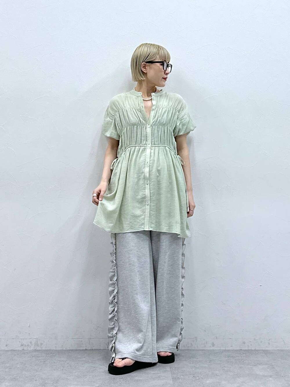 グレー系のスウェットパンツ、グリーン系のシャツ/ブラウス、ブラック系のサンダルを着用したレディースの夏コーディネートの2枚目の写真