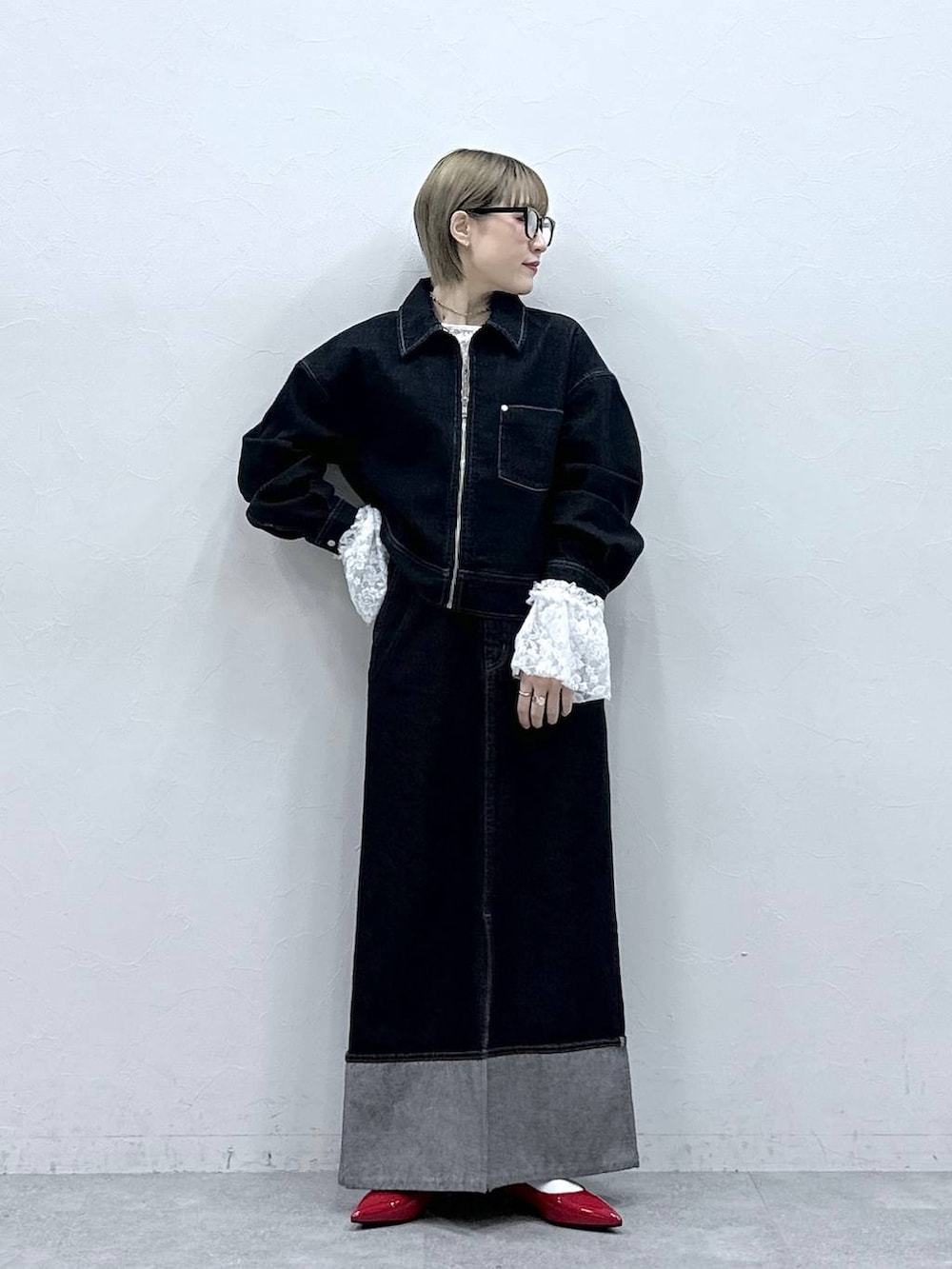 レッド系のパンプス、ブラック系のデニムジャケット、ブラック系のデニムスカートを着用したレディースの冬コーディネートの3枚目の写真