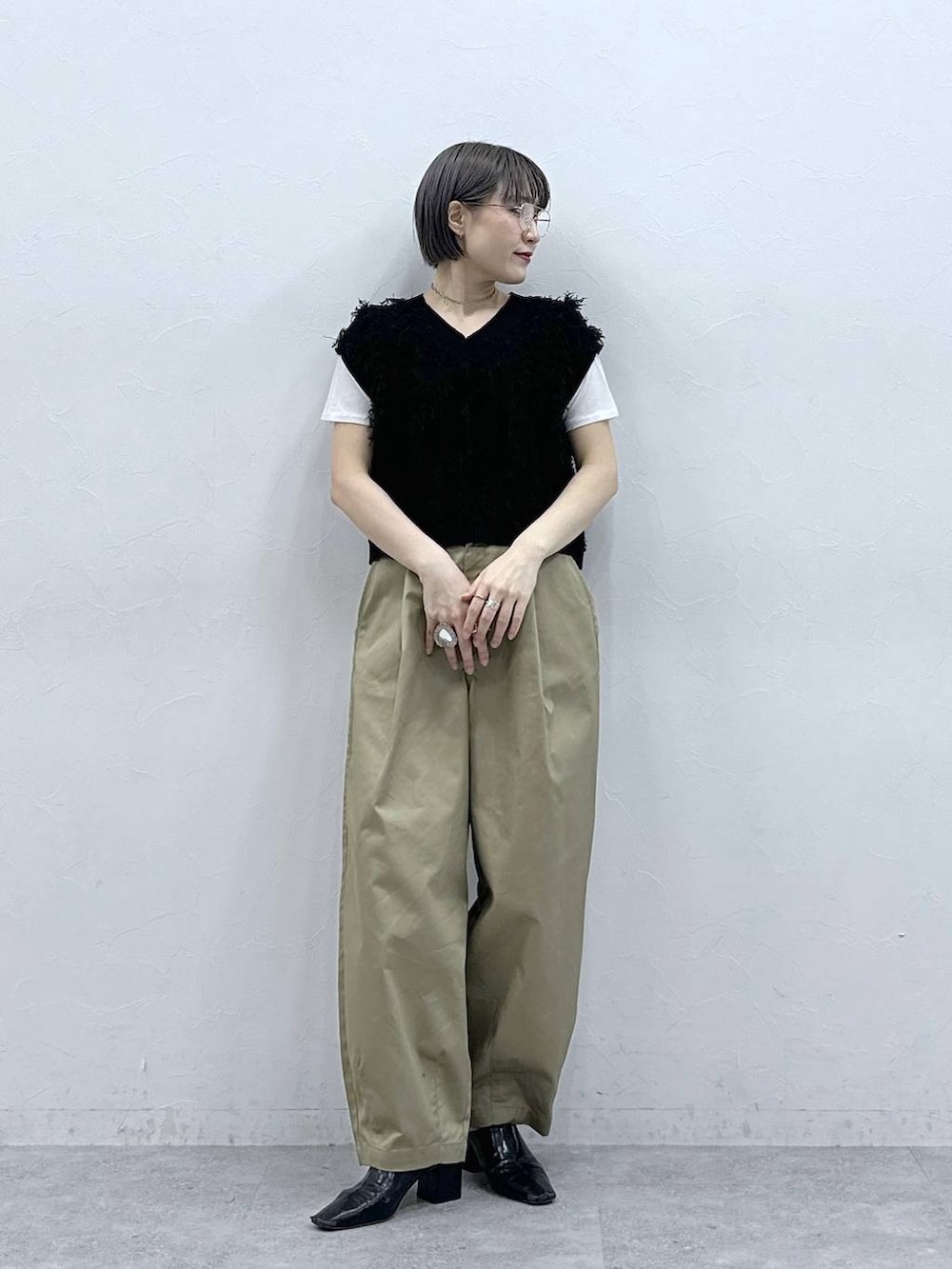 ベージュ系のチノパンツ、ホワイト系のTシャツ/カットソー、ブラック系のベストを着用したレディースの春コーディネートの2枚目の写真