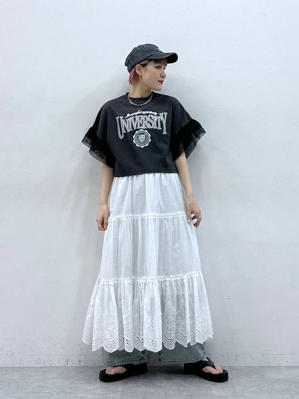 ブルー系のデニムパンツ、ブラック系のTシャツ/カットソー、ホワイト系のスカートを着用したレディースの春コーディネートの2枚目の写真