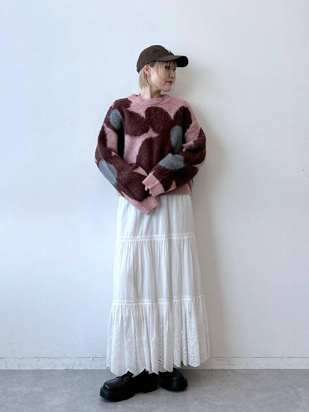 ブラック系のローファー、ピンク系のニット/セーター、ホワイト系のスカートを着用したレディースの秋コーディネートの3枚目の写真