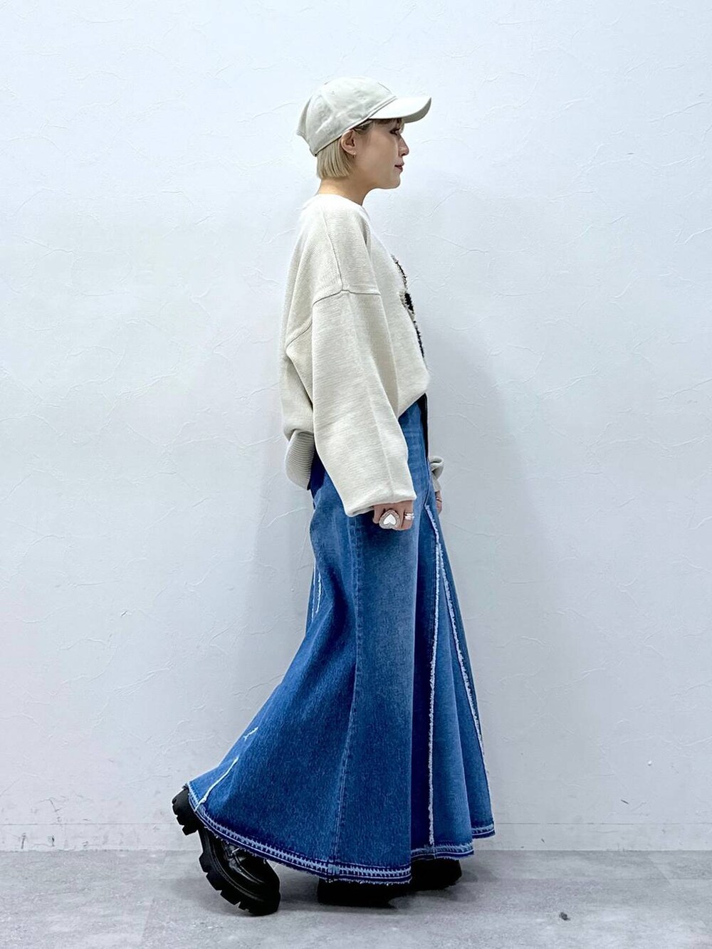 ブルー系のデニムスカート、ホワイト系のニット/セーター、ブラック系のローファーを着用したレディースの冬コーディネートの3枚目の写真