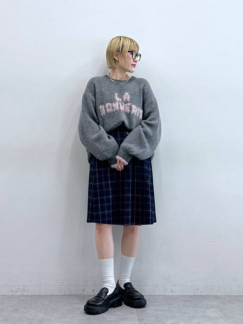 ブラック系のローファー、グレー系のニット/セーター、グリーン系のスカートを着用したレディースの秋コーディネートの2枚目の写真