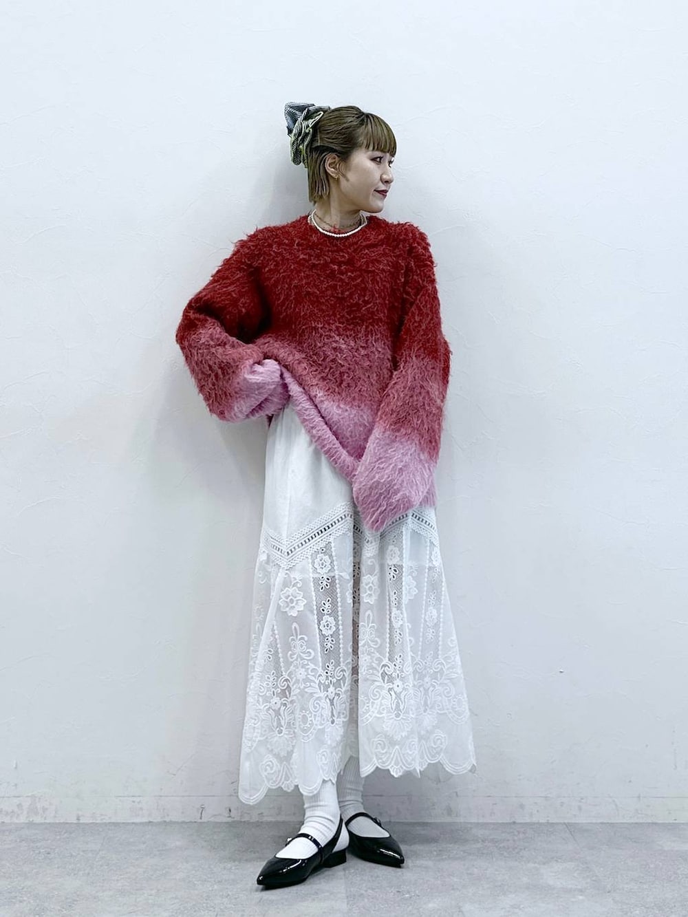 ホワイト系のスカート、レッド系のニット/セーター、ブラック系のパンプスを着用したレディースの冬コーディネートの3枚目の写真