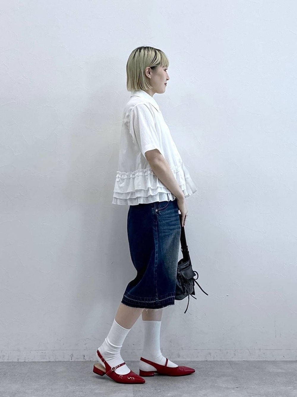 ブルー系のデニムパンツ、ブラック系のショルダーバッグ、レッド系のパンプスを着用したレディースの夏コーディネートの4枚目の写真
