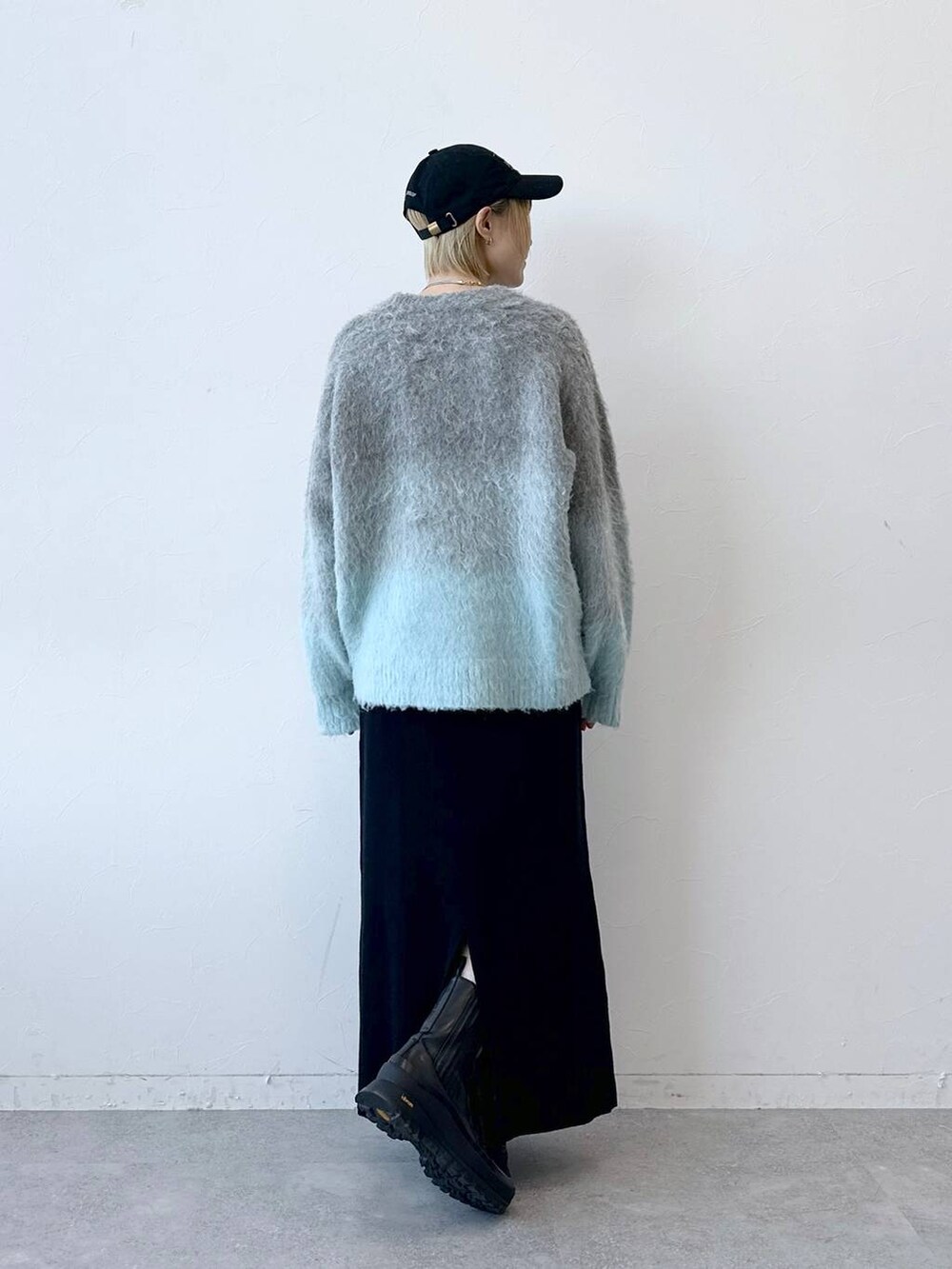 グレー系のニット/セーター、ブラック系のスカート、ブラック系のキャップを着用したレディースの秋コーディネートの6枚目の写真