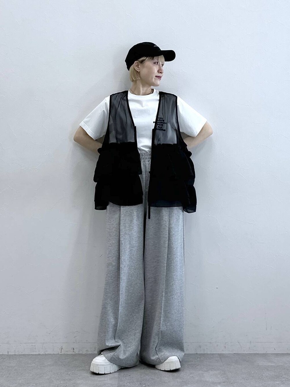 グレー系のスウェットパンツ、ホワイト系のTシャツ/カットソー、ブラック系のベストを着用したレディースの春コーディネートの4枚目の写真