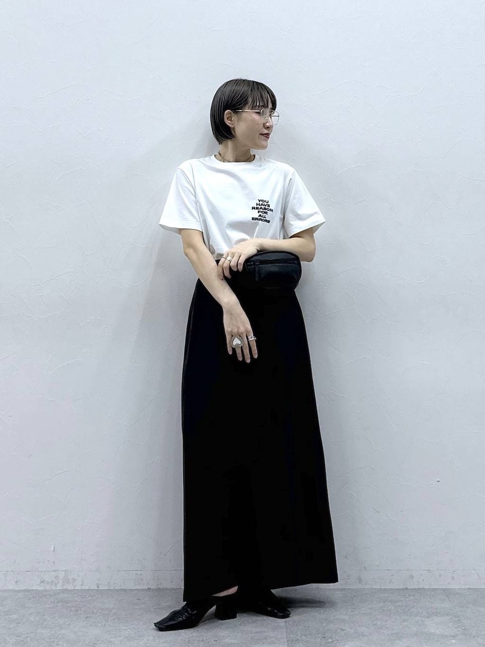 ブラック系のボディバッグ/ウエストポーチ、ブラック系のスカート、ホワイト系のTシャツ/カットソーを着用したレディースの春コーディネートの3枚目の写真