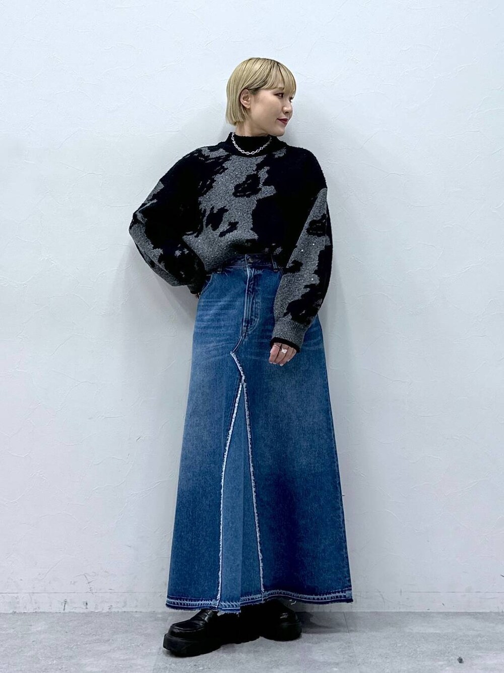 ブルー系のデニムスカート、ブラック系のニット/セーター、ブラック系のローファーを着用したレディースの冬コーディネートの6枚目の写真