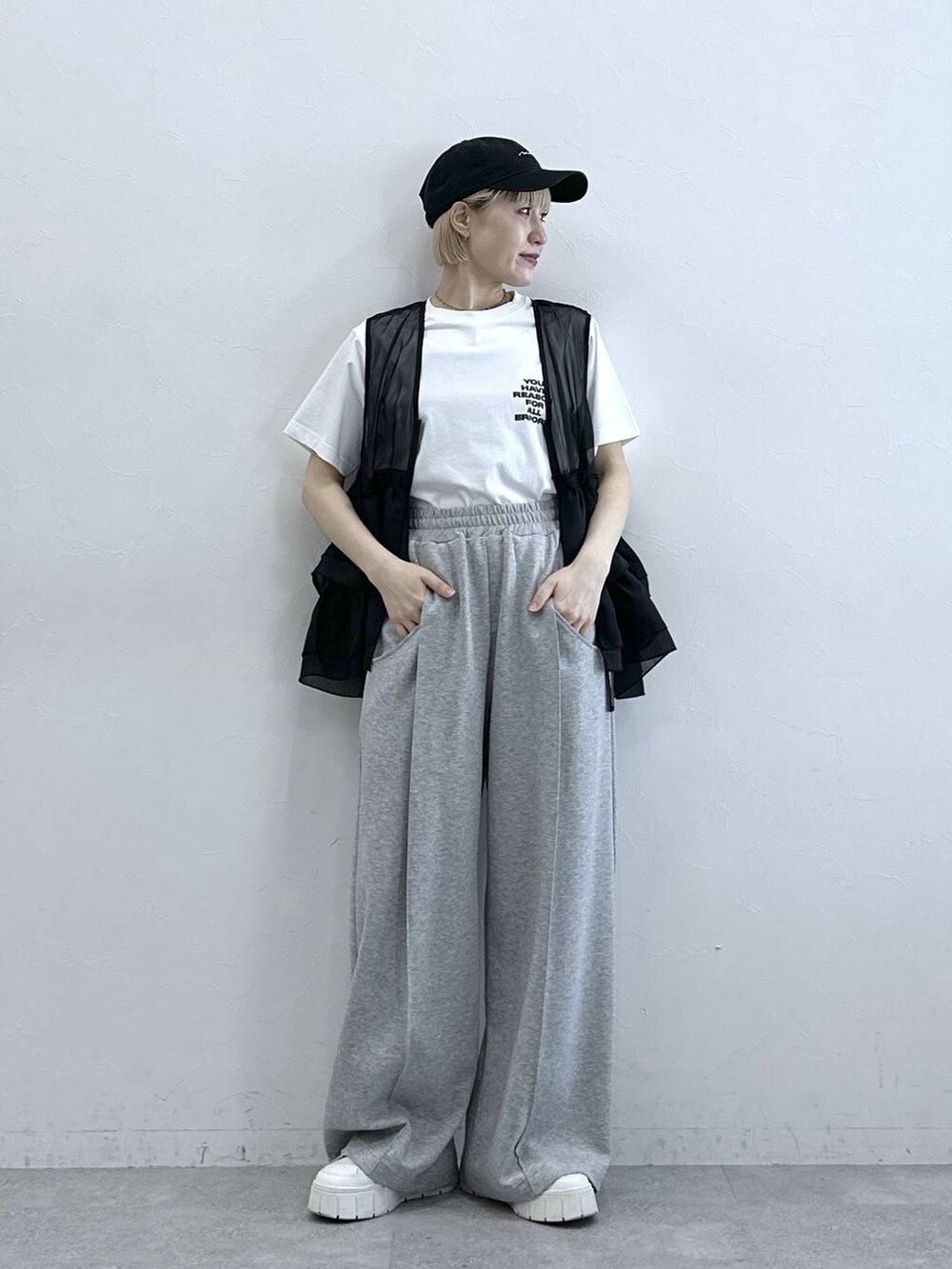 グレー系のスウェットパンツ、ホワイト系のTシャツ/カットソー、ブラック系のベストを着用したレディースの春コーディネートの3枚目の写真
