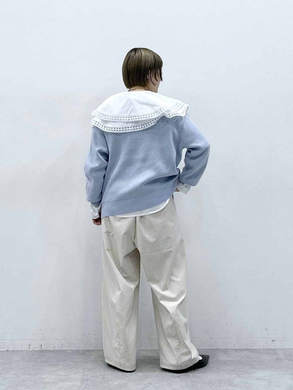 ホワイト系のチノパンツ、ホワイト系のシャツ/ブラウス、ブルー系のニット/セーターを着用したレディースの冬コーディネートの6枚目の写真