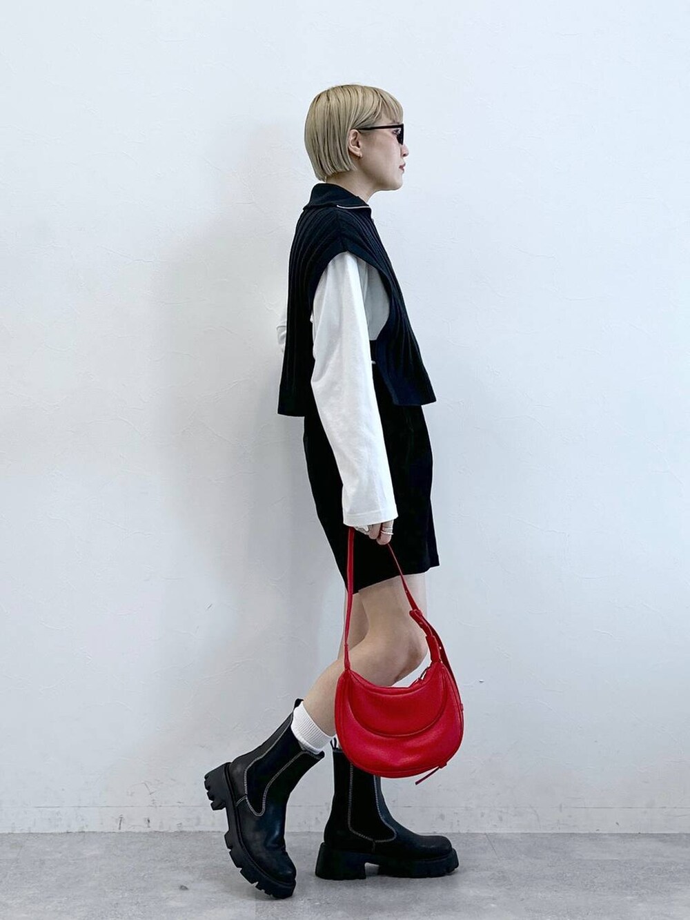 ブラック系のチノパンツ、レッド系のショルダーバッグ、ホワイト系のTシャツ/カットソーを着用したレディースの冬コーディネートの2枚目の写真