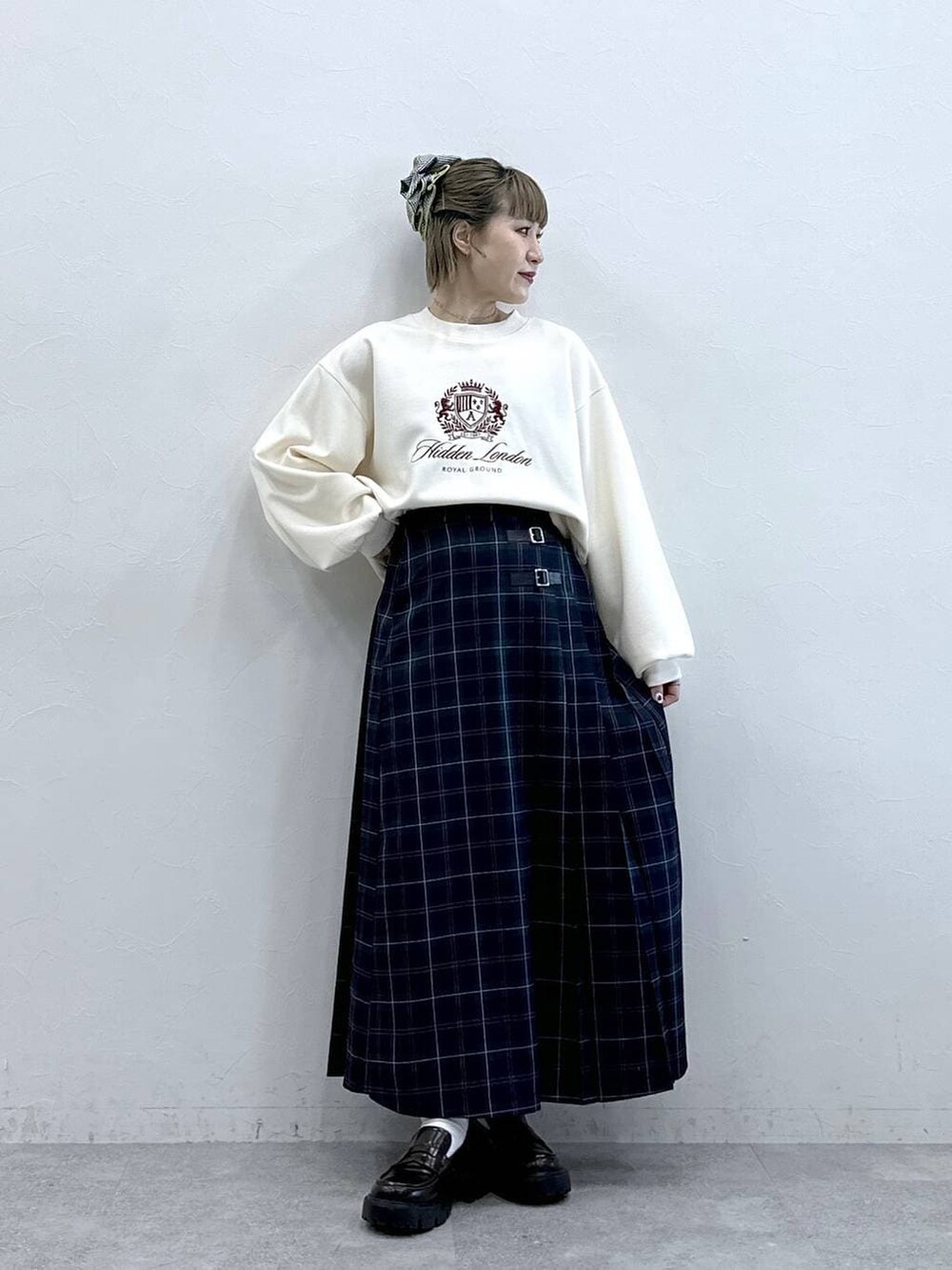 ブラウン系のローファー、グリーン系のスカート、ホワイト系のスウェットを着用したレディースの冬コーディネートの2枚目の写真