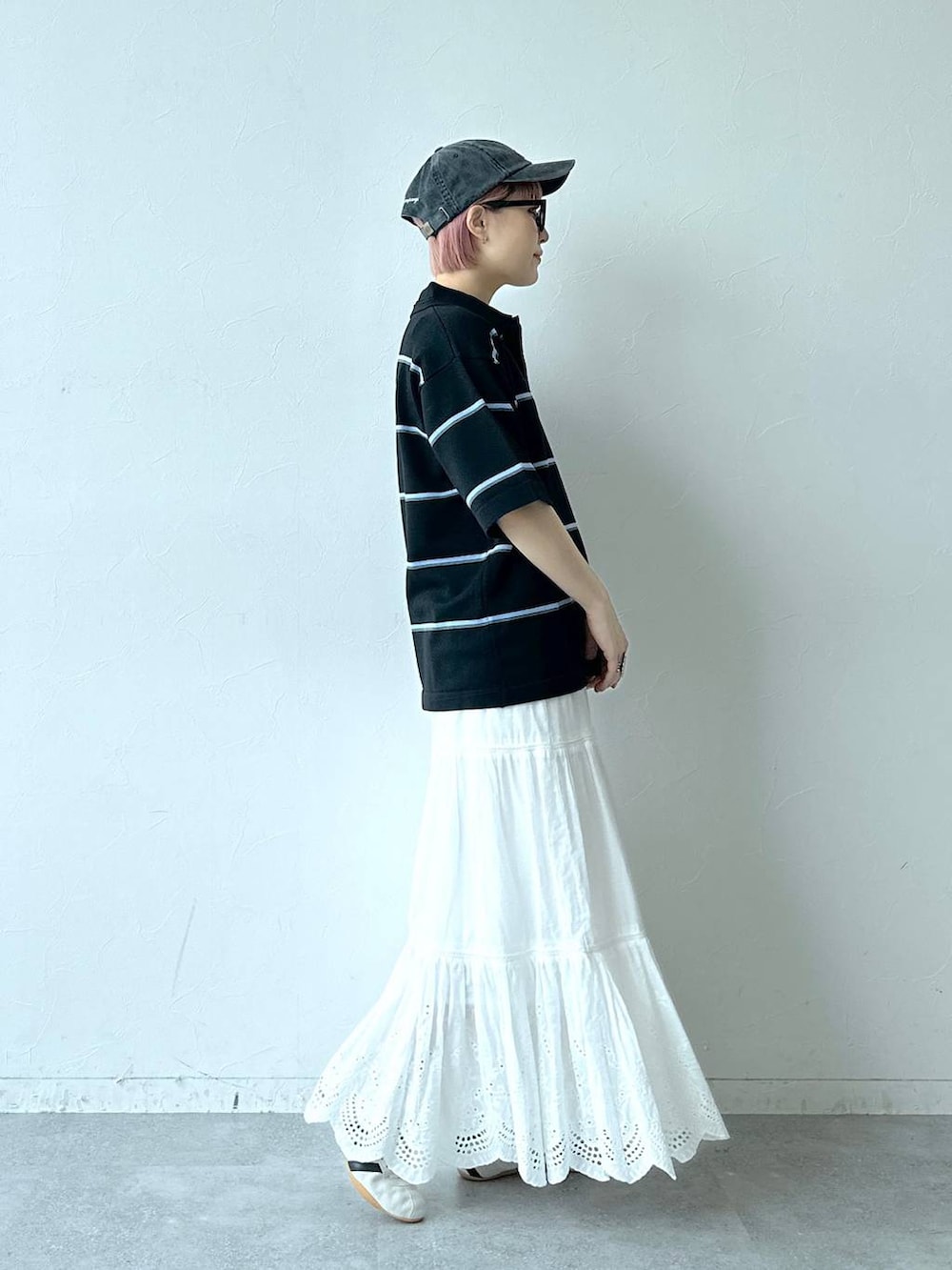 ホワイト系のスニーカー、ブラック系のポロシャツ、ホワイト系のスカートを着用したレディースの春コーディネートの4枚目の写真