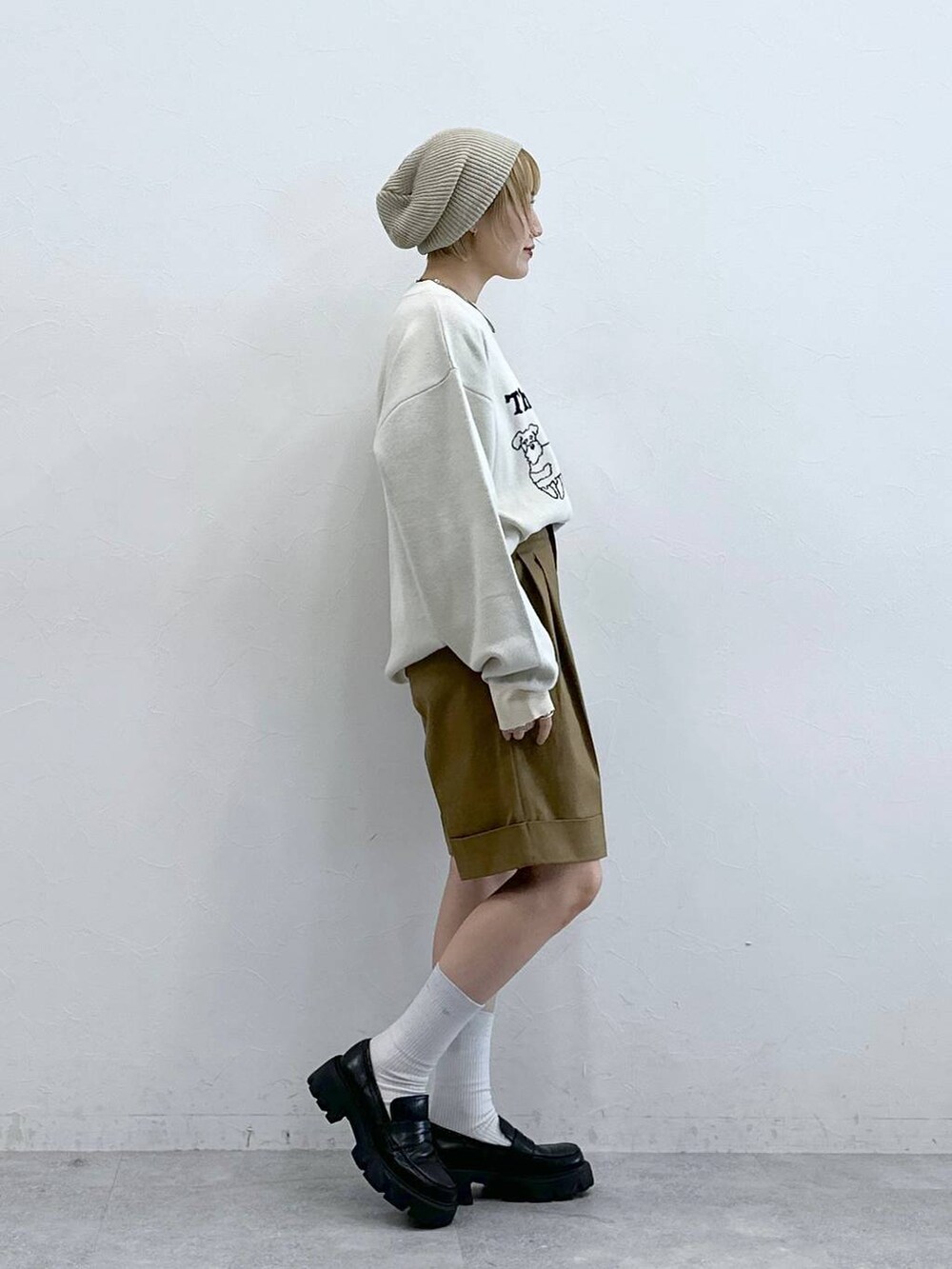 ホワイト系のニット/セーター、ブラック系のローファー、ブラウン系のチノパンツを着用したレディースの秋コーディネートの5枚目の写真