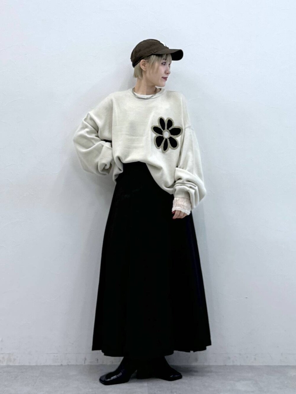 ホワイト系のニット/セーター、ブラウン系のスカート、ホワイト系のTシャツ/カットソーを着用したレディースの秋コーディネートの5枚目の写真