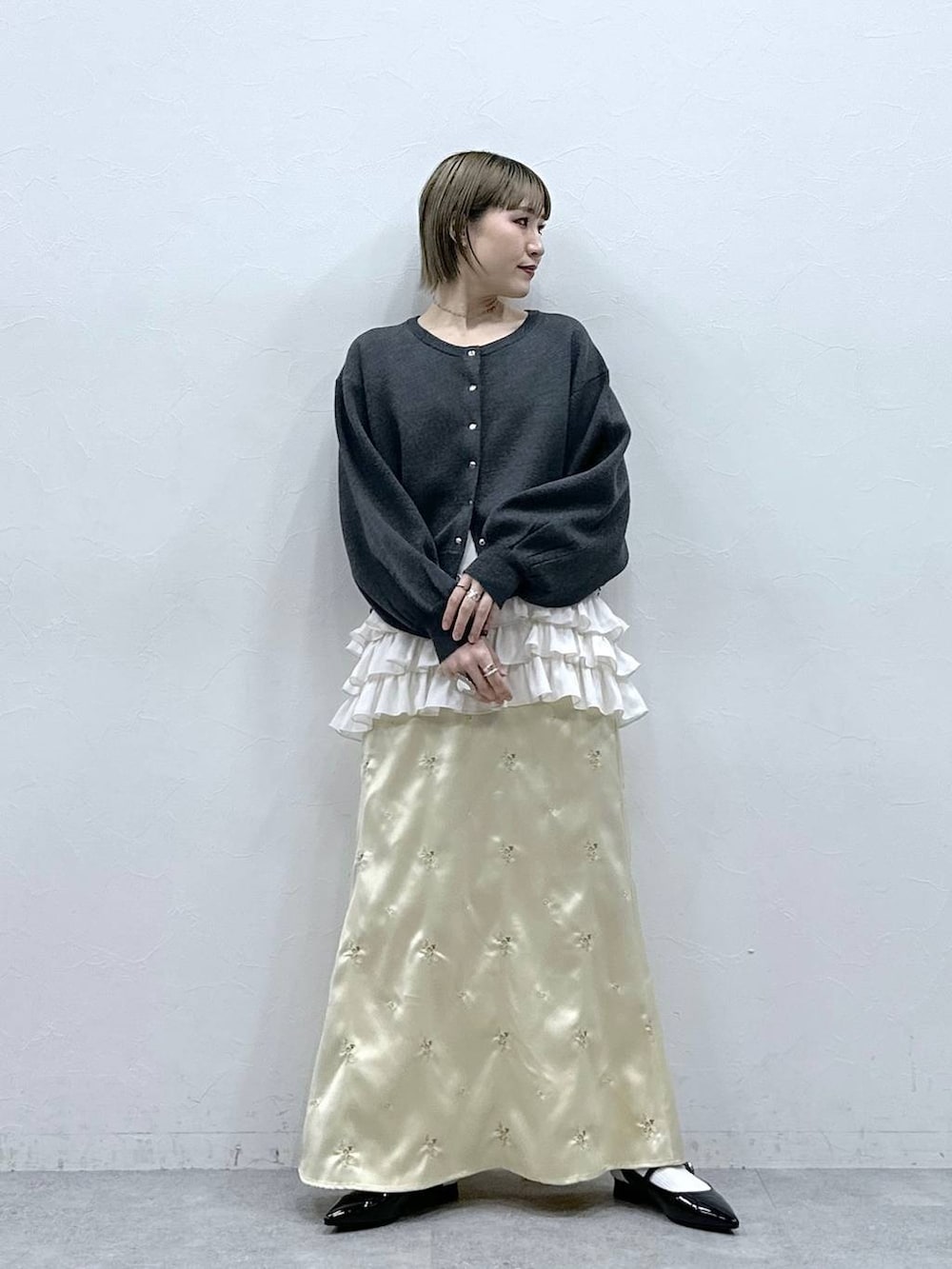 ホワイト系のキャミソール、ブラック系のパンプス、グレー系のカーディガン/ボレロを着用したレディースの冬コーディネートの3枚目の写真