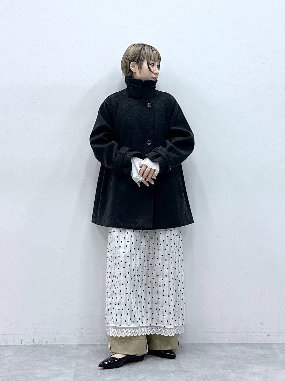 ブラック系のパンプス、ブラック系のステンカラーコート、ベージュ系のチノパンツを着用したレディースの冬コーディネートの5枚目の写真