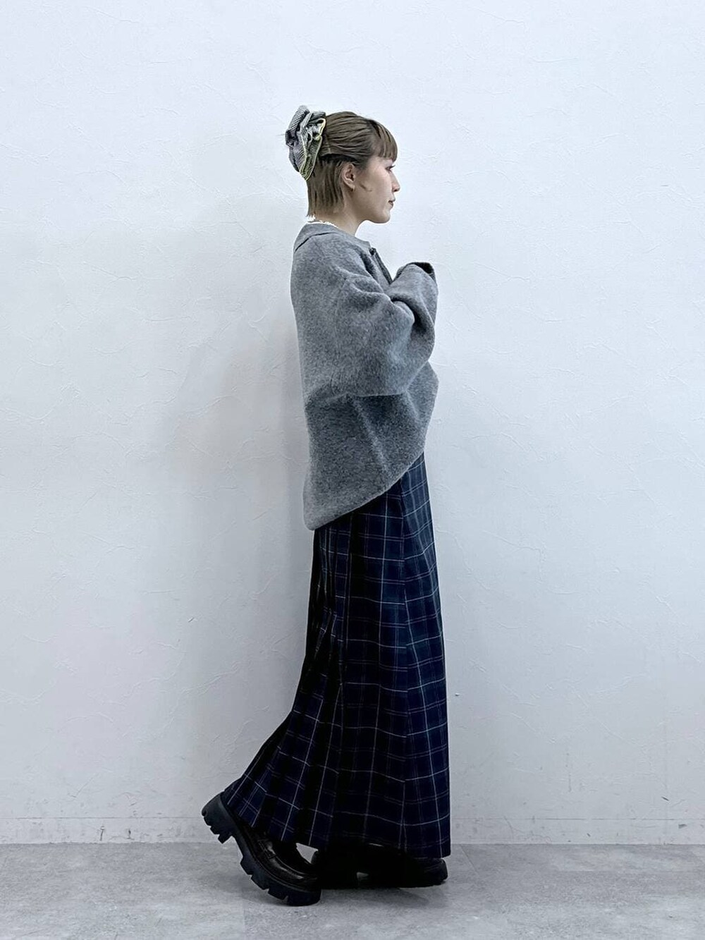 ブラック系のローファー、グリーン系のスカート、グレー系のポロシャツを着用したレディースの冬コーディネートの5枚目の写真