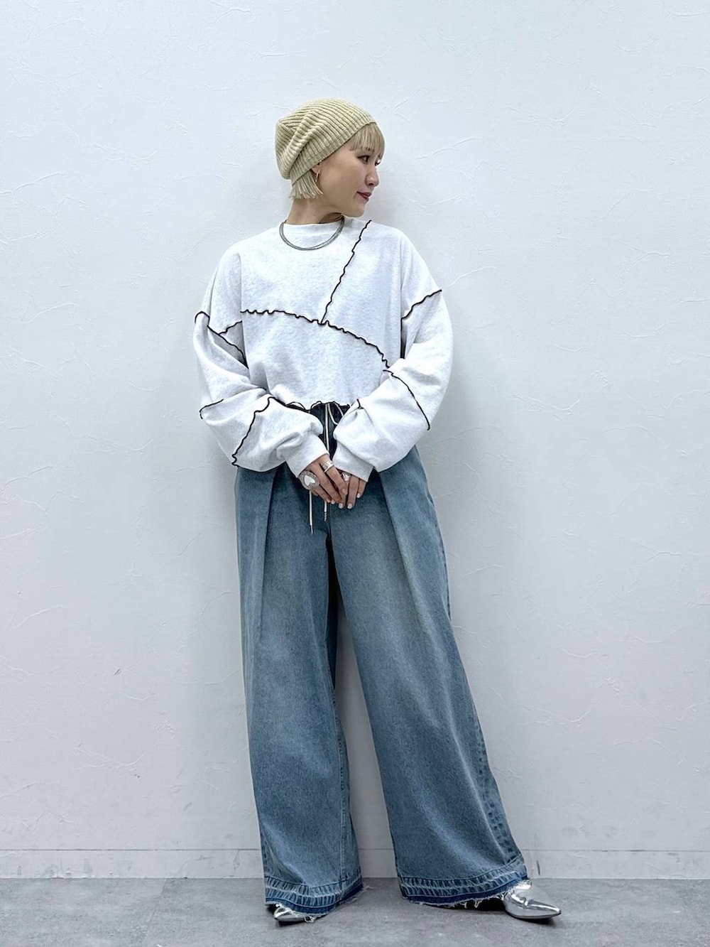 シルバー系のパンプス、ブルー系のデニムパンツ、ホワイト系のスウェットを着用したレディースの秋コーディネートの4枚目の写真