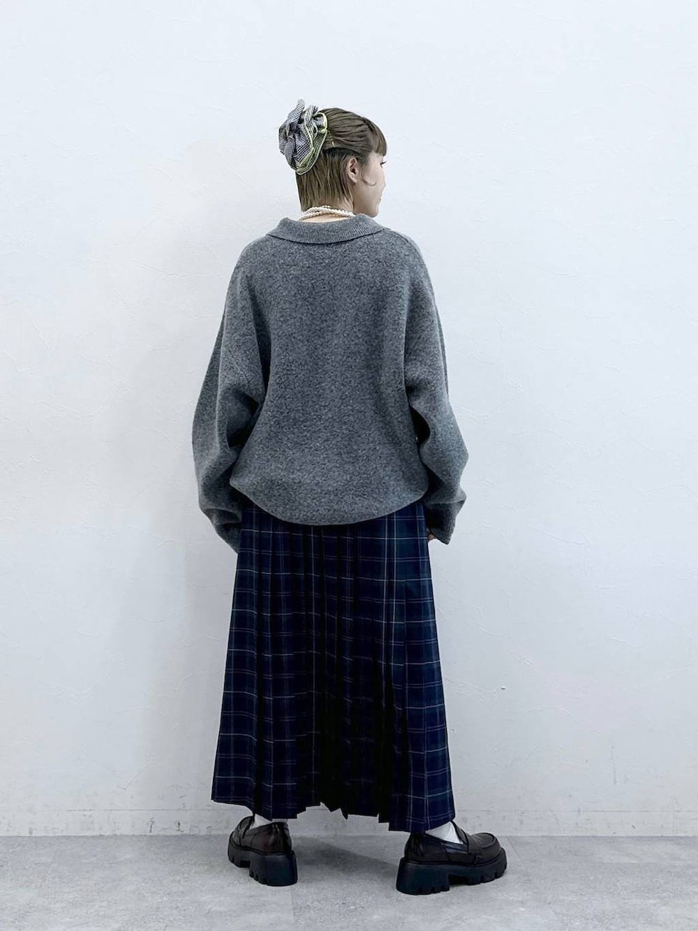 ブラック系のローファー、グリーン系のスカート、グレー系のポロシャツを着用したレディースの冬コーディネートの6枚目の写真