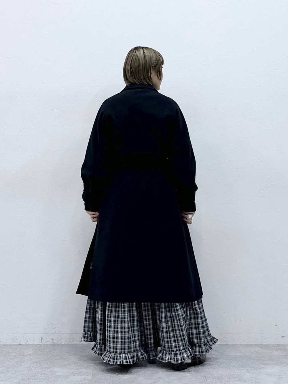 ブラック系のステンカラーコート、ブラック系のスカート、ブラック系のパンプスを着用したレディースの冬コーディネートの6枚目の写真