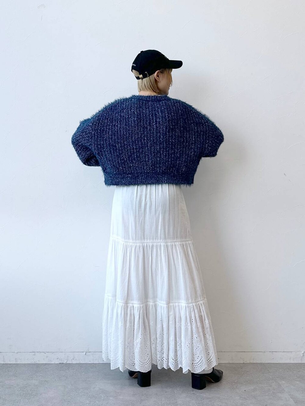 ブルー系のニット/セーター、ホワイト系のスカート、ブラック系のキャップを着用したレディースの秋コーディネートの6枚目の写真