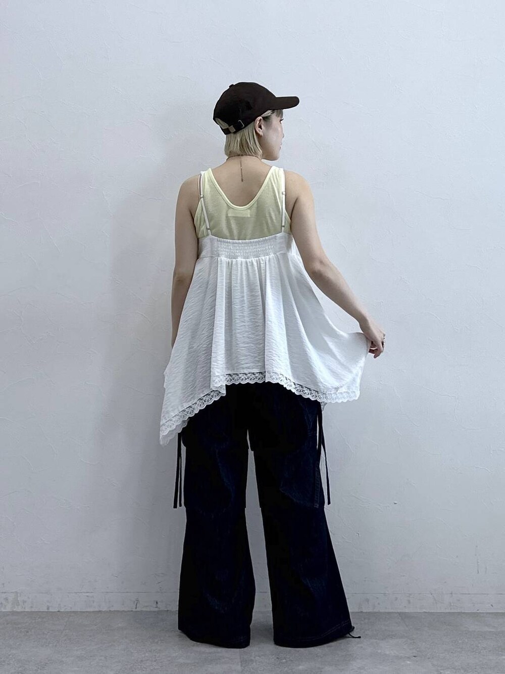 ブルー系のデニムパンツ、ブラック系のサンダル、ホワイト系のキャミソールを着用したレディースの夏コーディネートの5枚目の写真