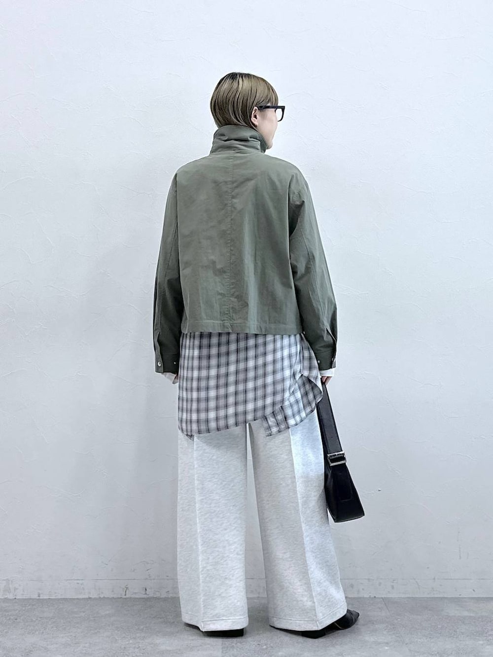 ホワイト系のスウェットパンツ、ブラック系のショルダーバッグ、グリーン系のブルゾンを着用したレディースの冬コーディネートの6枚目の写真