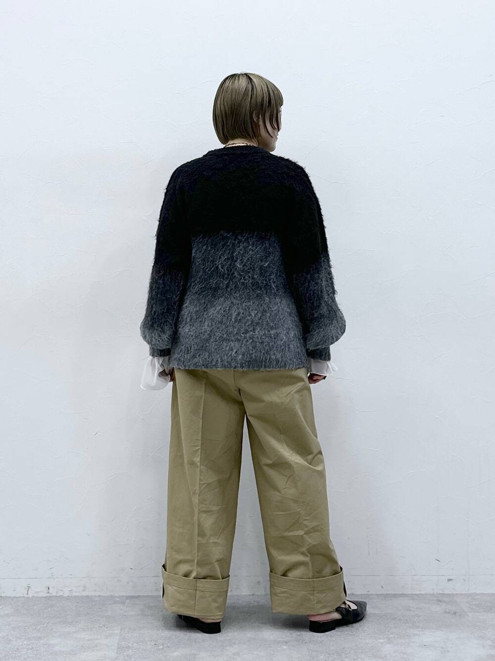 ブラック系のニット/セーター、ブラック系のパンプス、ベージュ系のチノパンツを着用したレディースの冬コーディネートの5枚目の写真