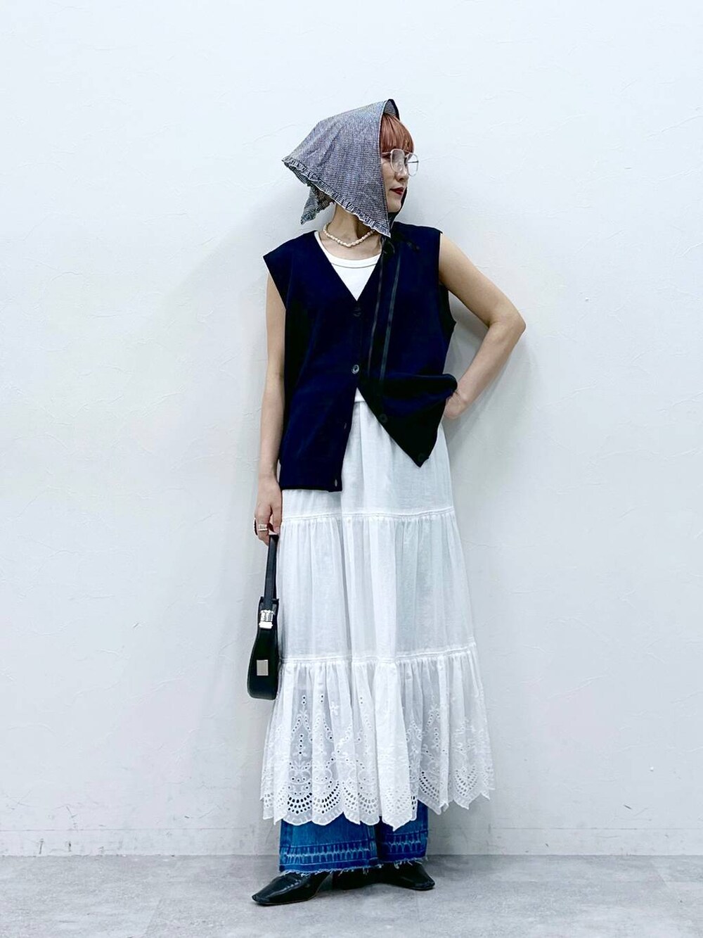 ブルー系のデニムパンツ、ブルー系のベスト、ホワイト系のタンクトップを着用したレディースの春コーディネートの2枚目の写真