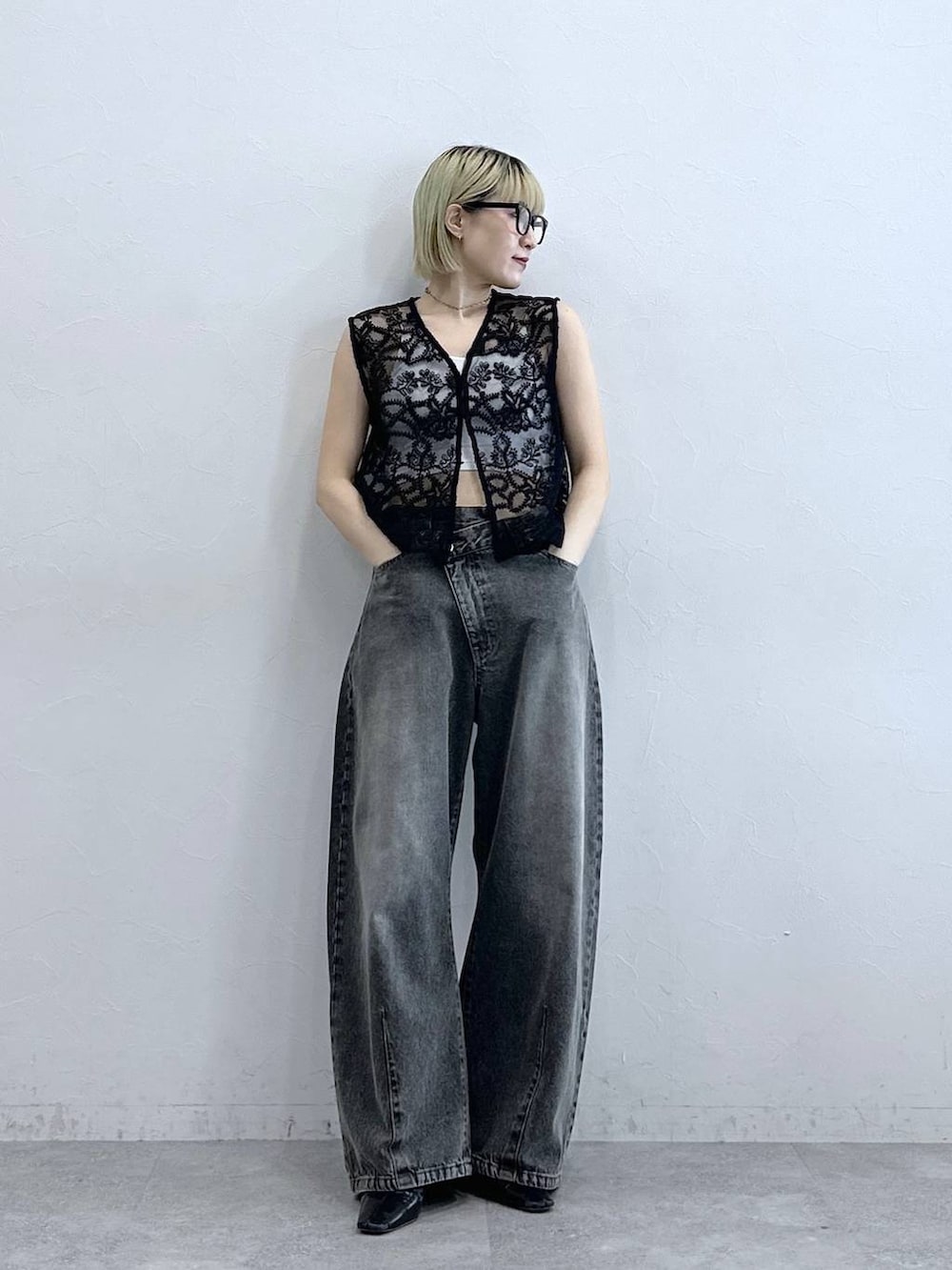 グレー系のデニムパンツ、ブラック系のベスト、ホワイト系のブラジャーを着用したレディースの夏コーディネートの3枚目の写真