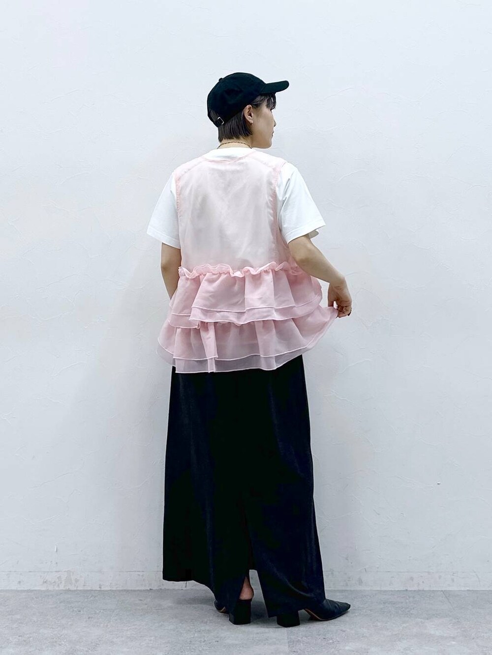 ブラック系のスカート、ホワイト系のTシャツ/カットソー、ピンク系のベストを着用したレディースの春コーディネートの5枚目の写真