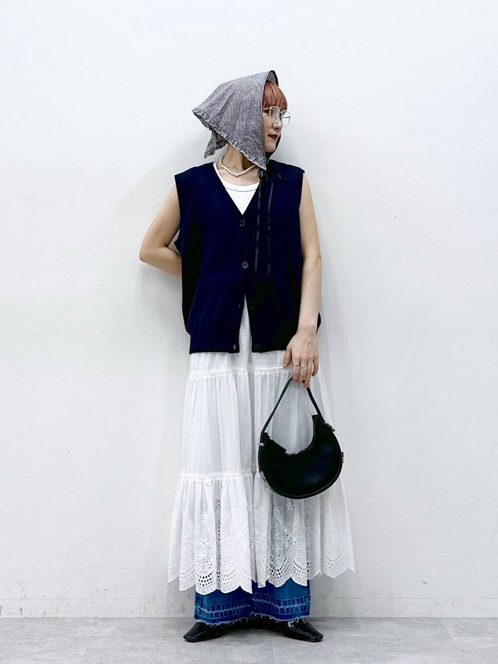 ブルー系のデニムパンツ、ブルー系のベスト、ホワイト系のタンクトップを着用したレディースの春コーディネートの3枚目の写真