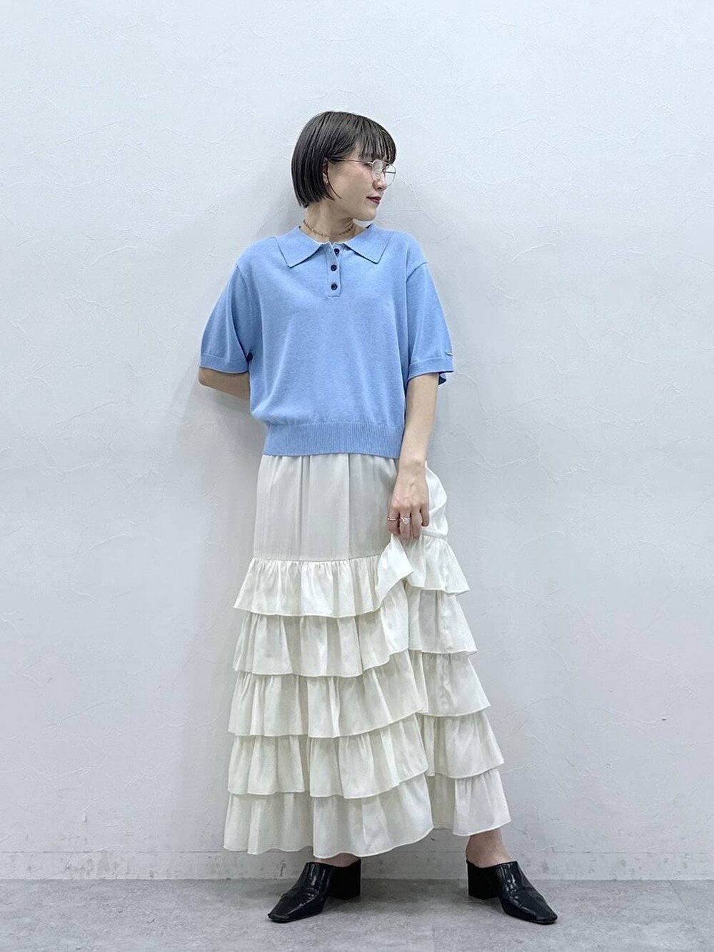 ブルー系のポロシャツ、ホワイト系のスカートを着用したレディースの春コーディネートの4枚目の写真