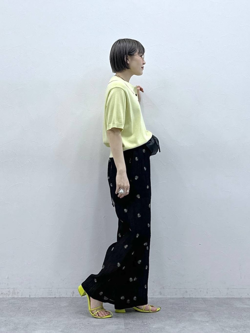 ブラック系のボディバッグ/ウエストポーチ、イエロー系のポロシャツ、ブラック系のスラックスを着用したレディースの春コーディネートの5枚目の写真