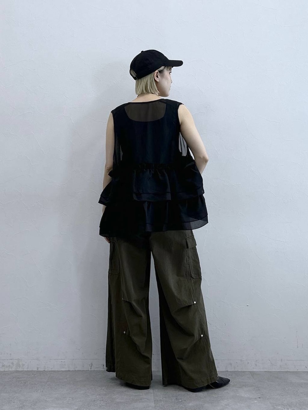 グリーン系のカーゴパンツ、ブラック系のタンクトップ、ブラック系のベストを着用したレディースの夏コーディネートの5枚目の写真