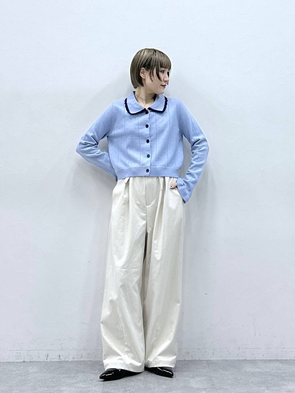 ホワイト系のチノパンツ、ブルー系のカーディガン/ボレロ、ブラック系のパンプスを着用したレディースの冬コーディネートの2枚目の写真