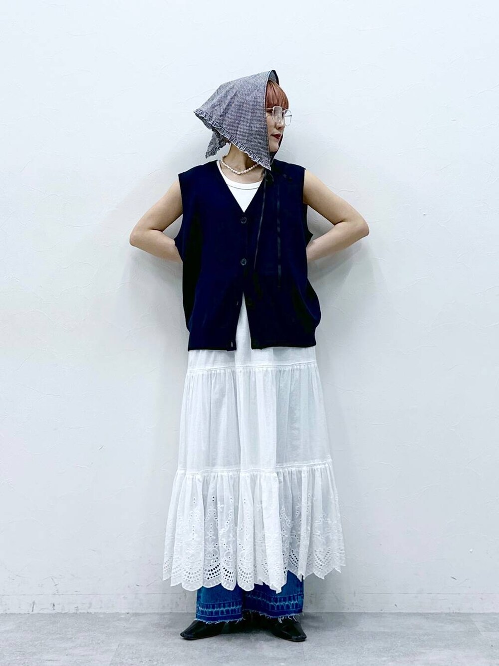 ブルー系のデニムパンツ、ブルー系のベスト、ホワイト系のタンクトップを着用したレディースの春コーディネートの4枚目の写真